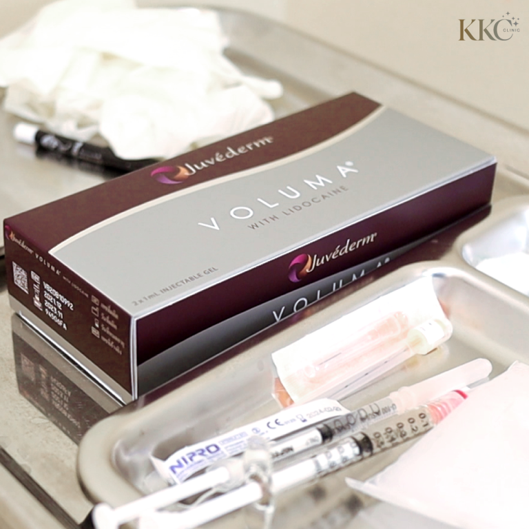กล่อง Juvederm Voluma with Lidocaine วางอยู่บนถาดแพทย์ ถัดจากกล่องมีเข็มฉีดยาและอุปกรณ์ทางการแพทย์อื่นๆ รวมถึงถุงมือและวัสดุบรรจุภัณฑ์