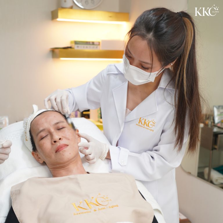 พญ.วรวรรณ เตชะสมบูรณ์ ที่ KKC Clinic กำลังทำการรักษาร้อยไหมบนใบหน้าผู้ป่วย โดยทำงานอย่างเบามือขณะที่ผู้ป่วยนอนหลับตาและสวมผ้ากันเปื้อนของคลินิก