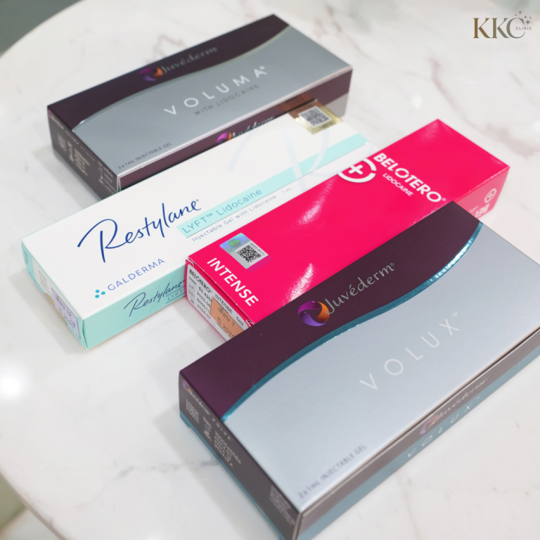 กล่องฟิลเลอร์หลายยี่ห้อรวมถึง Juvederm Voluma, Juvederm Volux, Restylane Lyft และ Belotero Intense วางอยู่บนโต๊ะหินอ่อนสีขาวที่ KKC Clinic