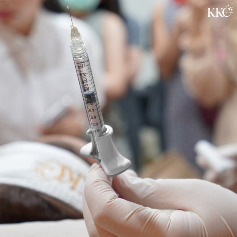 ภาพโคลสอัพของมือที่สวมถุงมือจับเข็มฉีดยาที่มีสารฉีด เตรียมพร้อมสำหรับการทำหัตถการเสริมความงาม