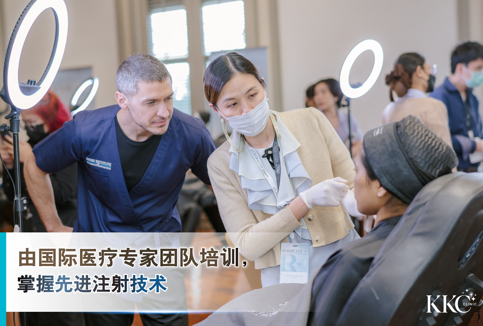 医疗培训现场，国际医疗专家团队监督美学注射操作。一位戴口罩和手套的女性从业者正在为坐着的患者注射，一位男性培训师在旁仔细观察。