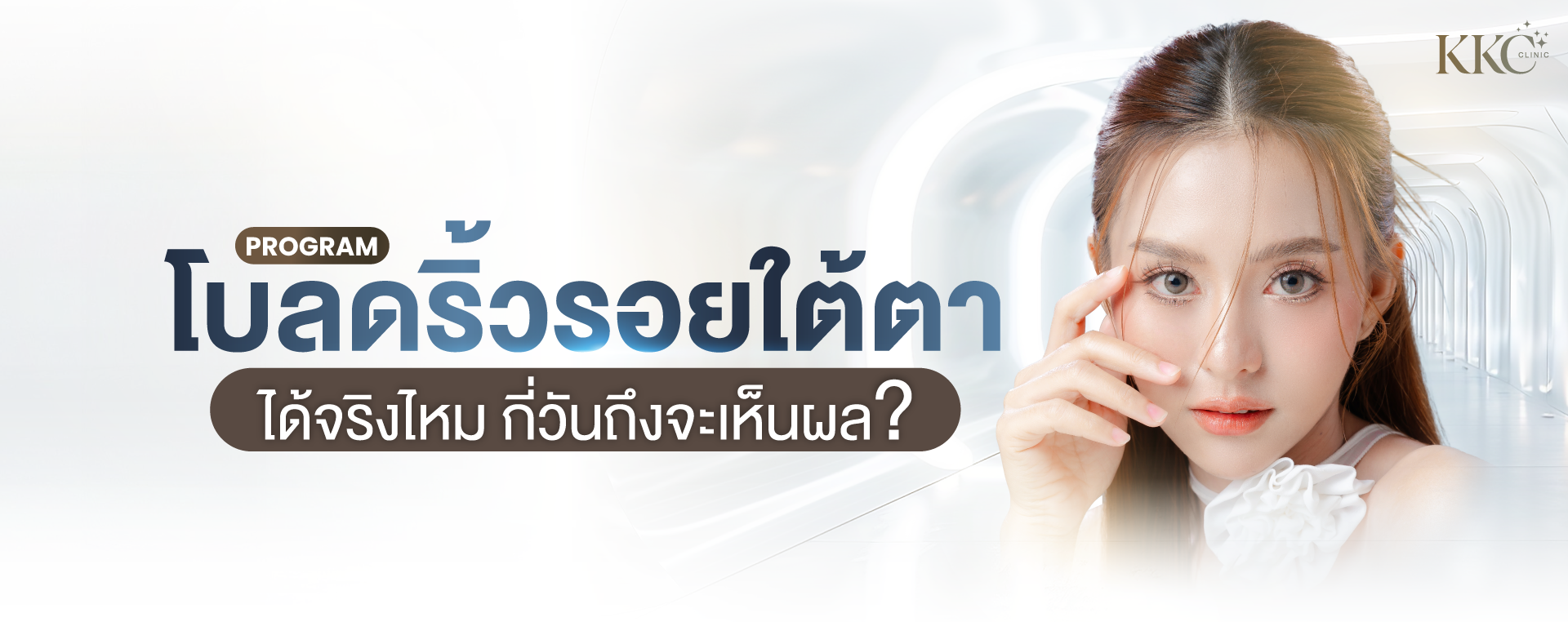 ภาพระยะใกล้ของผู้หญิงผิวเนียนใส กำลังสัมผัสบริเวณใต้ตา เพื่อโปรโมทโปรแกรมโบท็อกซ์ใต้ตา ฉากหลังเป็นโถงทางเดินสมัยใหม่ที่มีแสงสว่าง