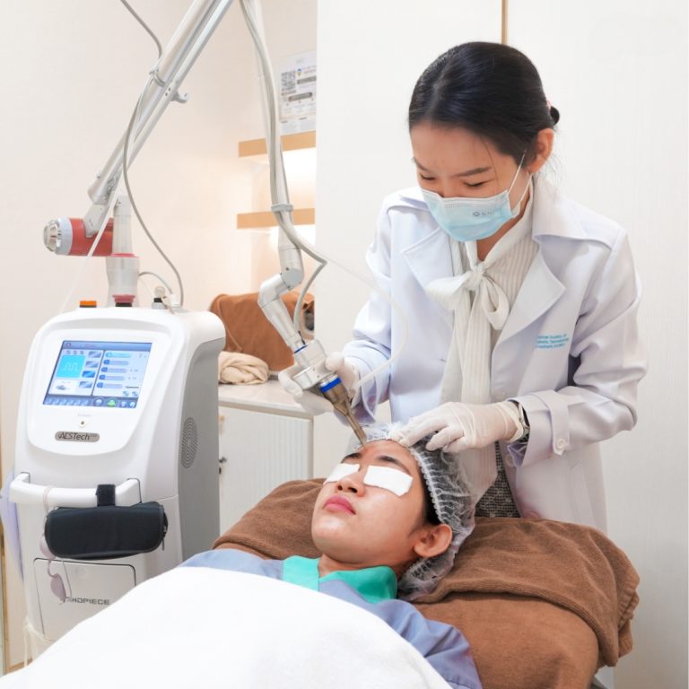 Doctor performing CO₂ laser treatment on a patient's forehead.