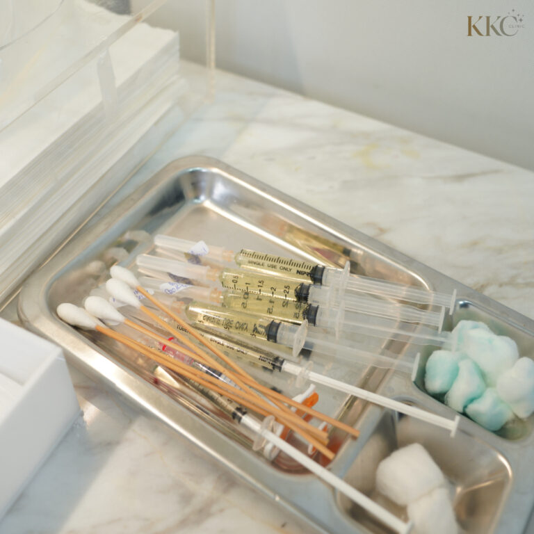 Sterile tray prepared with syringes filled with fat-dissolving solution, cotton swabs, and medical tools for injection.