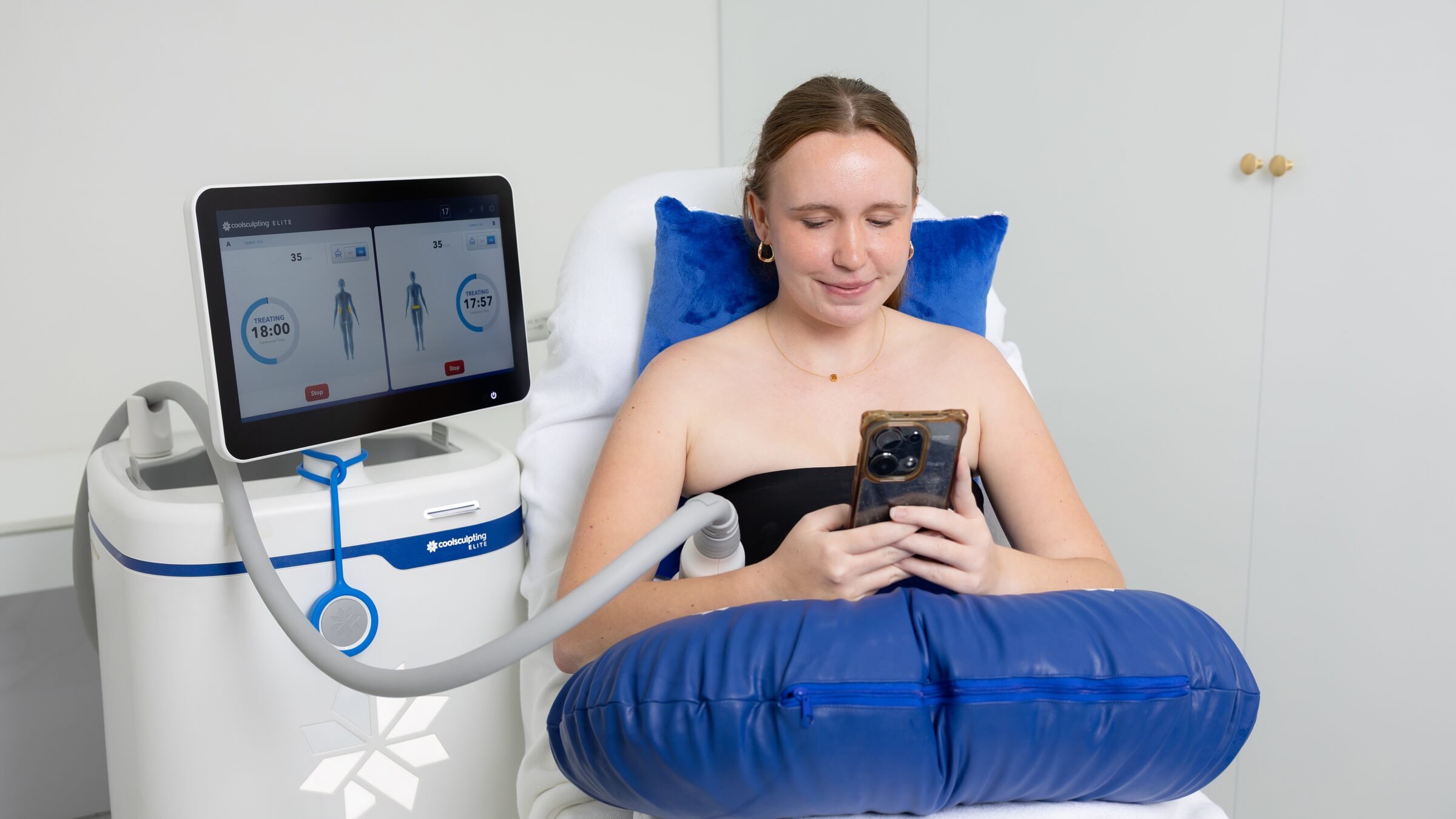 A client reads her phone during a CoolSculpting Elite cooling cycle